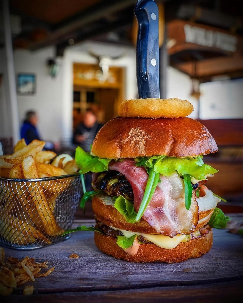 Burger s kolutićem luka na terasi restorana
